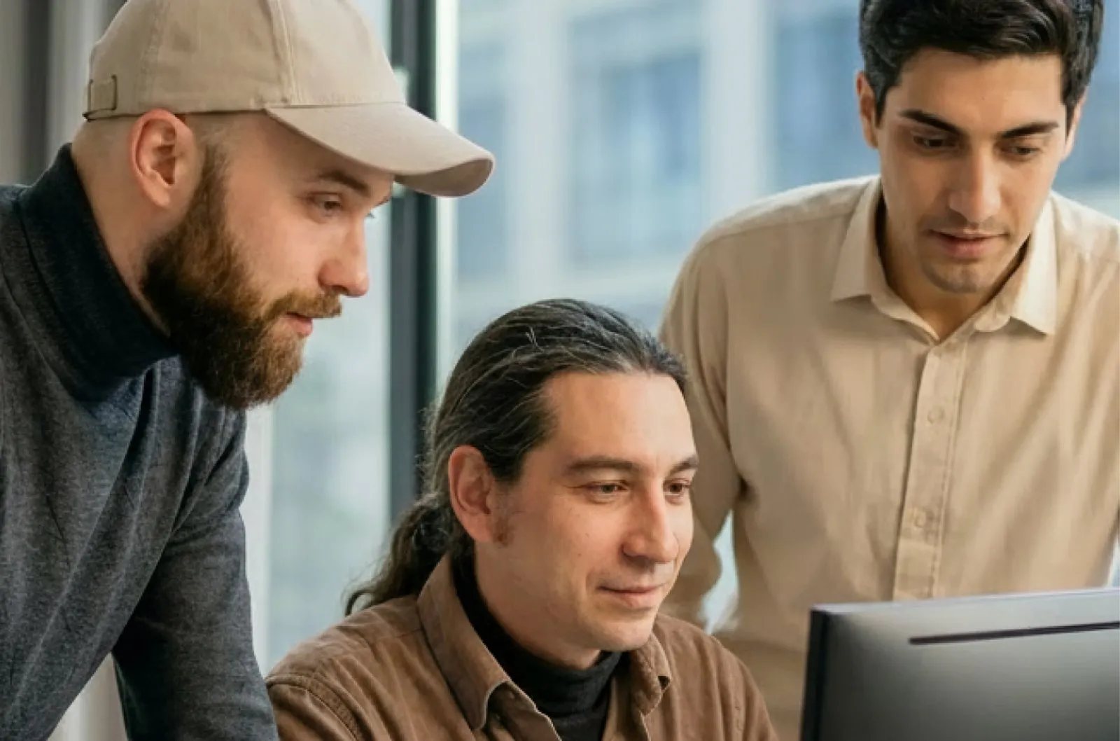 Drei Mitarbeiter von TenMedia besprechen gemeinsam eine Softwarelösung am Bildschirm im Berliner Büro