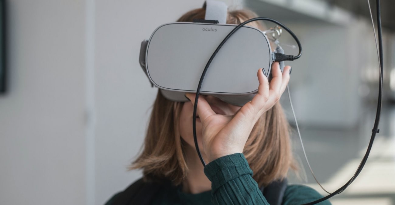 Frau im grünen Pulli schaut in eine graue Virtual Reality Brille
