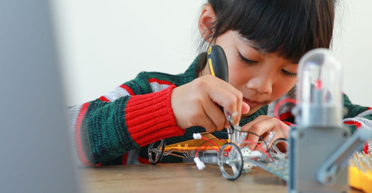 Programmieren lernen: Kind bastelt an Roboter