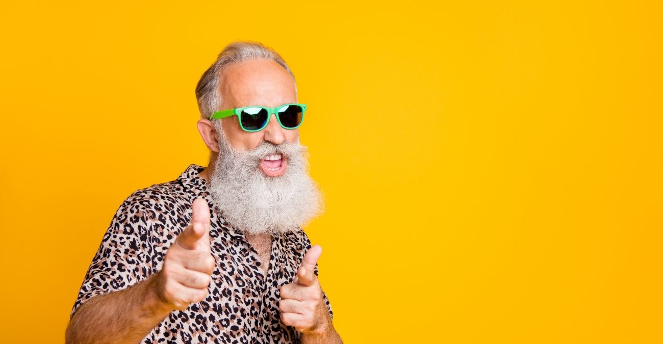 Ein älterer Herr mit weißem Bart. Er trägt Sonnenbrille und Hemd mit Leopardenmuster. Er macht eine coole Geste, denn er freut sich auf die neuen Trends in der Softwareentwicklung.