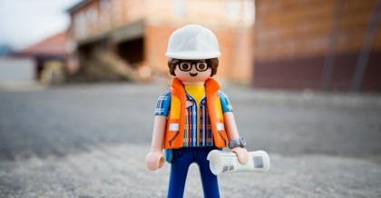 Ein Bauarbeiter in Form eines Legomännchens steht auf einer Asphaltstrasse. Ein Symbolbild für: Systemwartung.