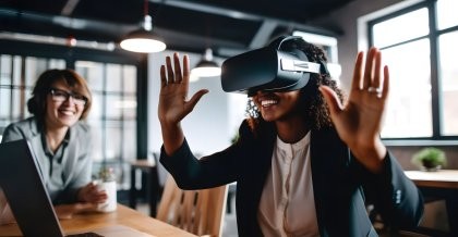 Eine dynamische junge Geschäftsfrau sitzt mit einer VR-Brille vor ihrem Notebook. Freudestrahlend testet sie VR im Business-Bereich.