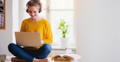Eine Frau im Schneidersitz erstellt am Laptop eine Website mit einem CMS.